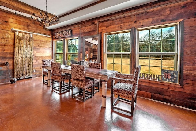 dining space with finished concrete flooring, wood walls, and a notable chandelier