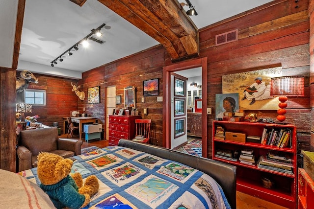 bedroom with track lighting, visible vents, and wooden walls