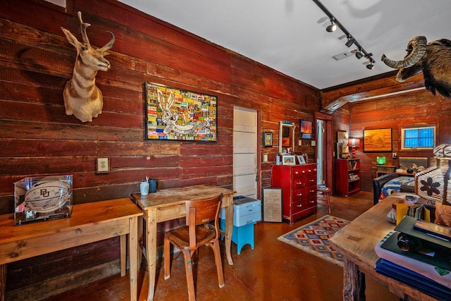 dining space with track lighting and wooden walls