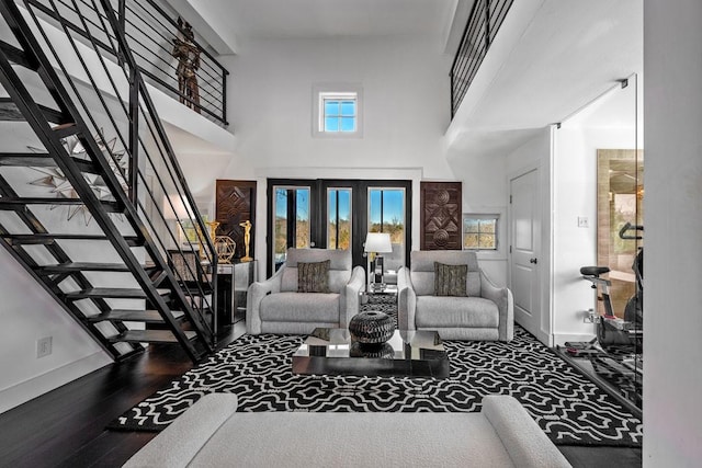 living room with a towering ceiling, stairway, a wealth of natural light, and wood finished floors