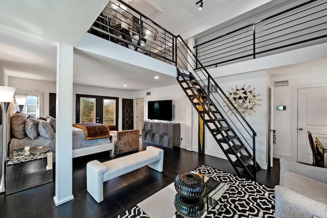 living room featuring dark wood-type flooring, a towering ceiling, baseboards, french doors, and stairway