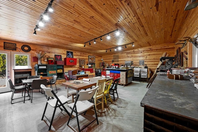 dining space featuring wood ceiling, wooden walls, track lighting, and concrete flooring