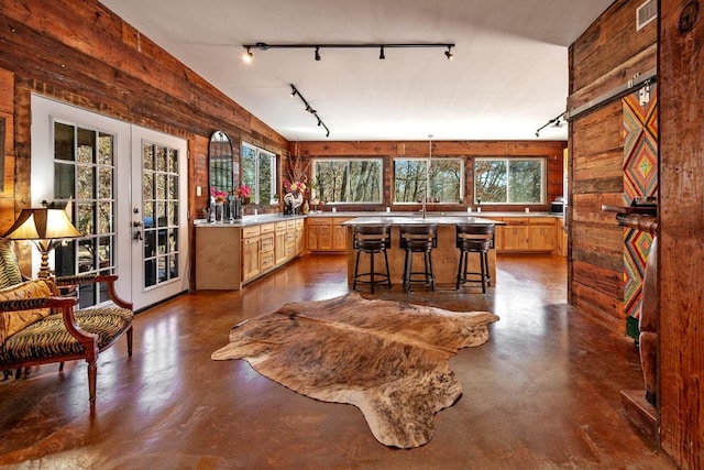 kitchen with wooden walls, french doors, concrete floors, and track lighting