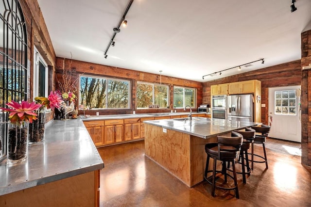 kitchen with rail lighting, concrete floors, stainless steel appliances, and a sink