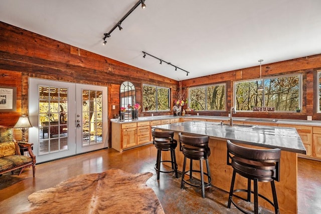 kitchen featuring track lighting, a kitchen breakfast bar, concrete flooring, and french doors