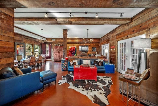 living room featuring a notable chandelier, wood walls, french doors, beam ceiling, and rail lighting