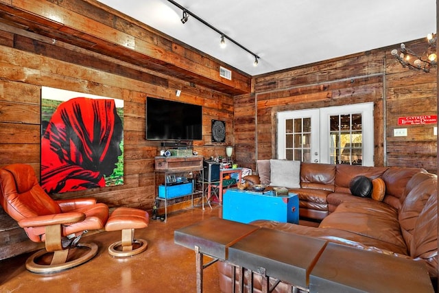 living room featuring french doors, finished concrete flooring, visible vents, wood walls, and track lighting