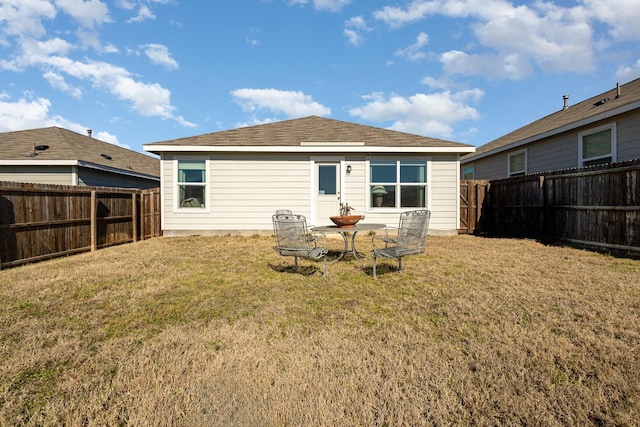 rear view of house featuring a yard and a fenced backyard