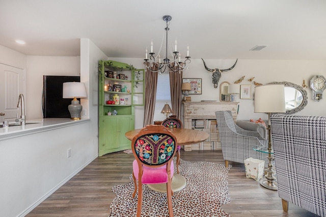 dining space with baseboards, wood finished floors, visible vents, and an inviting chandelier