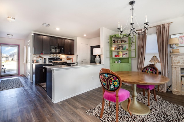 kitchen featuring visible vents, stove, dark wood-type flooring, black microwave, and a sink