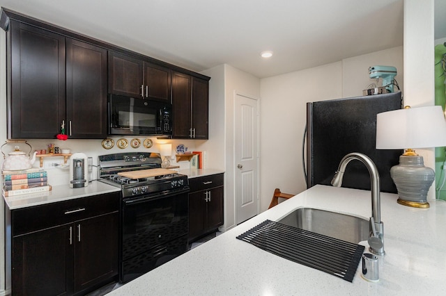 kitchen with light stone counters, recessed lighting, dark brown cabinetry, a sink, and black appliances