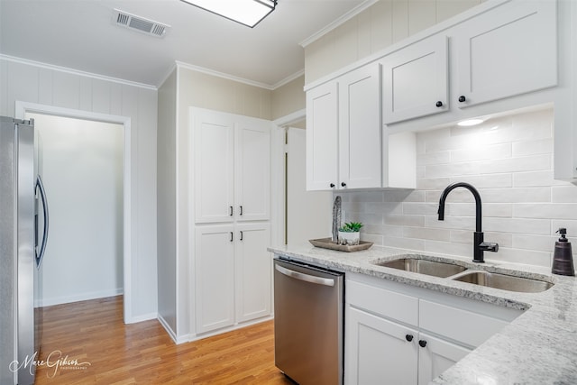 kitchen with visible vents, ornamental molding, stainless steel appliances, light wood-style floors, and a sink