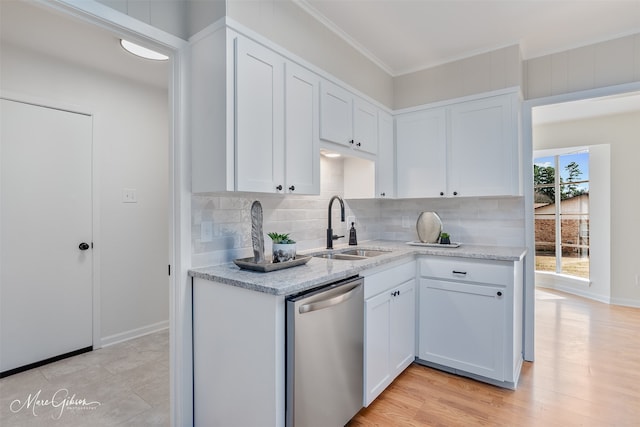 kitchen featuring crown molding, decorative backsplash, stainless steel dishwasher, white cabinetry, and a sink