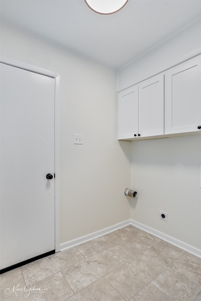 washroom with cabinet space, electric dryer hookup, and baseboards