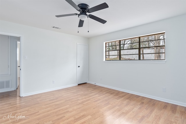 empty room with light wood-style floors, baseboards, visible vents, and ceiling fan