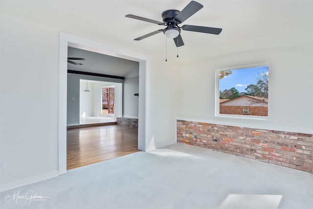 unfurnished room with baseboards, ceiling fan, and brick wall