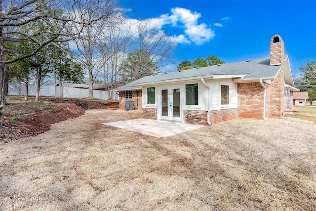 rear view of house featuring brick siding, fence, french doors, a chimney, and a patio area