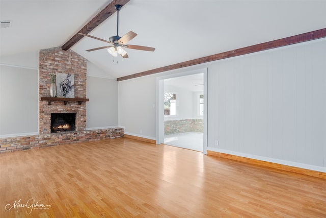 unfurnished living room featuring lofted ceiling with beams, ceiling fan, a fireplace, and wood finished floors