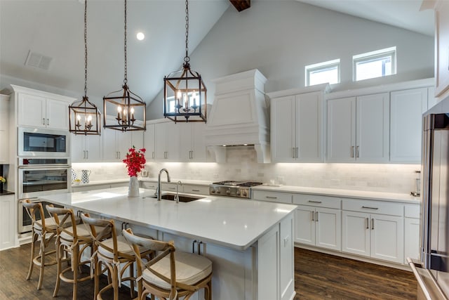 kitchen featuring dark wood-type flooring, a center island with sink, a sink, and visible vents