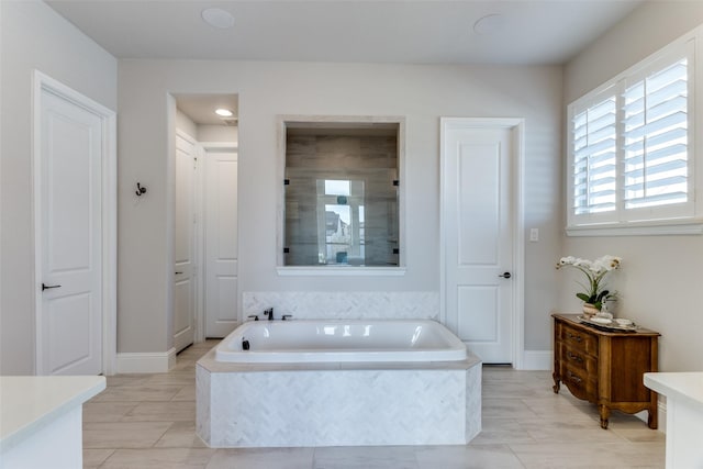 full bathroom featuring a shower stall, baseboards, and a bath