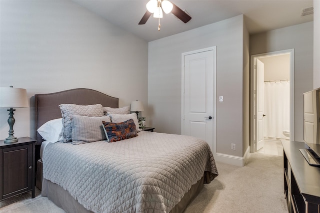 bedroom featuring light carpet, baseboards, visible vents, ensuite bath, and ceiling fan