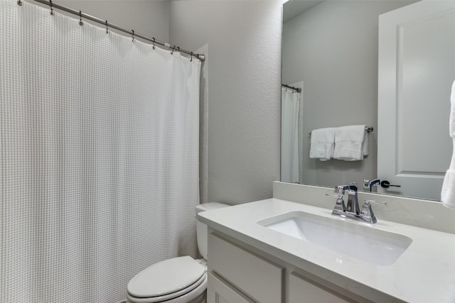 full bathroom featuring a textured wall, curtained shower, vanity, and toilet