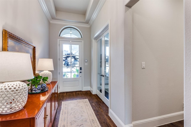 doorway to outside featuring ornamental molding, a raised ceiling, dark wood finished floors, and baseboards