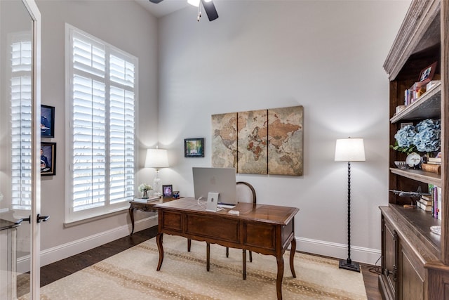 office space featuring a ceiling fan, baseboards, and wood finished floors