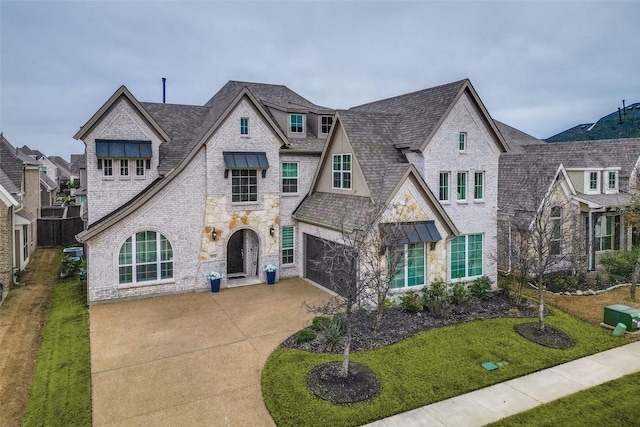 french country style house with a front yard, concrete driveway, brick siding, and an attached garage