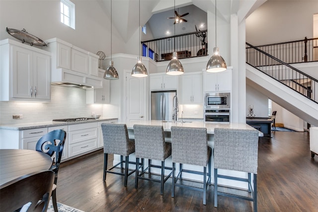 kitchen featuring light stone counters, dark wood-style flooring, white cabinetry, a kitchen breakfast bar, and appliances with stainless steel finishes