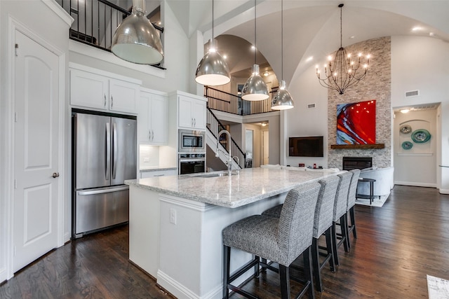 kitchen with a sink, a fireplace, appliances with stainless steel finishes, and dark wood-style flooring