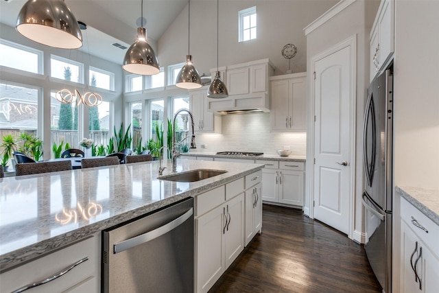 kitchen with pendant lighting, tasteful backsplash, appliances with stainless steel finishes, white cabinetry, and a sink