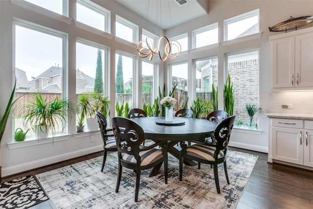 sunroom with a healthy amount of sunlight, a notable chandelier, and visible vents