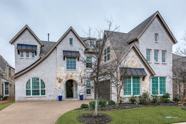 view of front of property with a front yard, stone siding, brick siding, and driveway