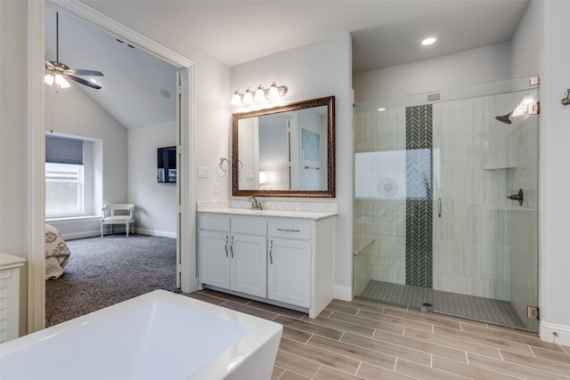 full bath featuring a ceiling fan, a stall shower, vaulted ceiling, vanity, and baseboards