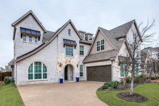 view of front of house featuring brick siding, an attached garage, stone siding, driveway, and a front lawn