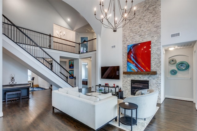 living room with a fireplace, wood finished floors, visible vents, stairs, and an inviting chandelier