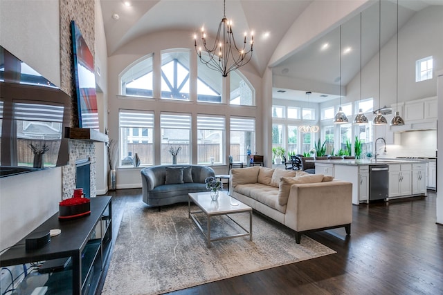 living room featuring dark wood-style floors, high vaulted ceiling, a fireplace, and a notable chandelier