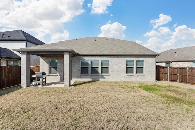 back of property with a patio, a yard, a fenced backyard, and brick siding