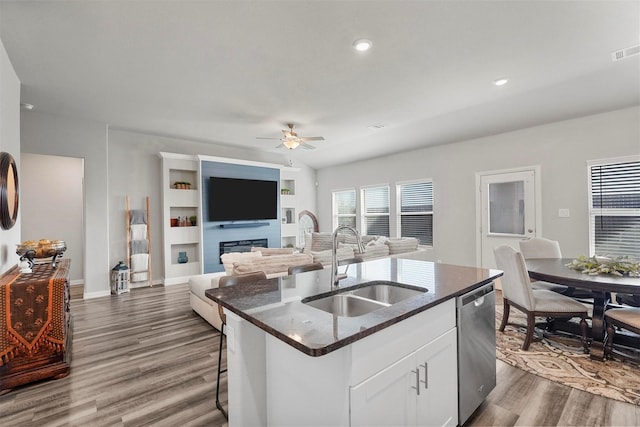 kitchen with dishwasher, a glass covered fireplace, dark wood-type flooring, and a sink