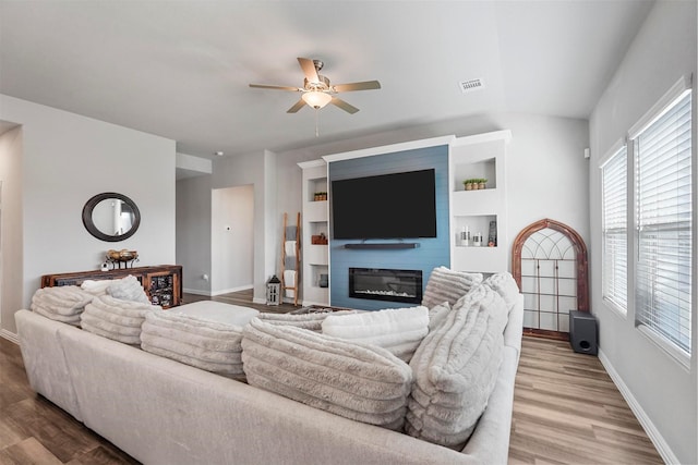 living room with visible vents, a ceiling fan, a glass covered fireplace, wood finished floors, and baseboards