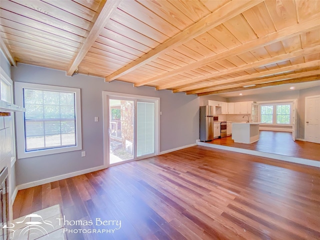 unfurnished living room featuring wooden ceiling, light wood-style floors, baseboards, and beam ceiling