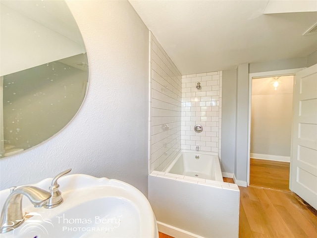 full bath featuring  shower combination, a sink, baseboards, and wood finished floors