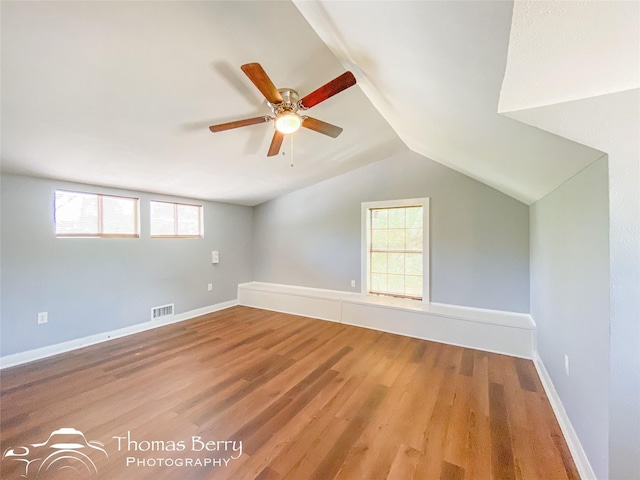 additional living space with lofted ceiling, baseboards, visible vents, and wood finished floors