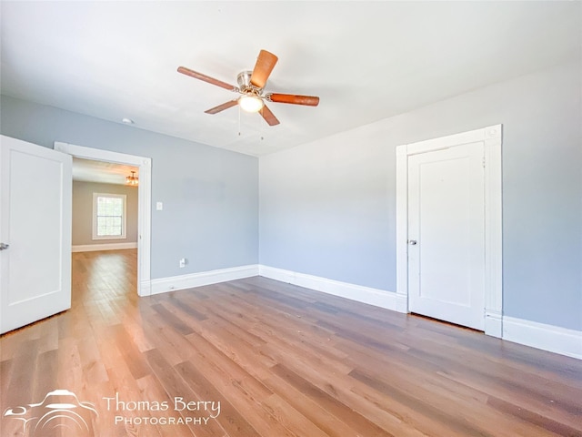 unfurnished room with a ceiling fan, light wood-type flooring, and baseboards