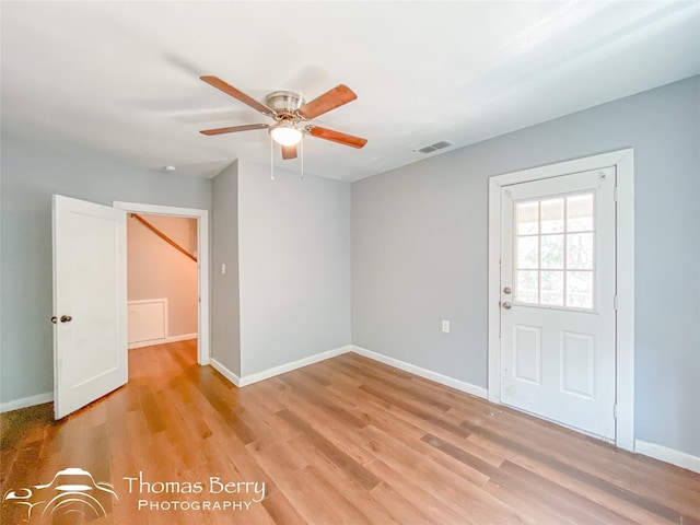 empty room featuring a ceiling fan, baseboards, visible vents, and light wood finished floors