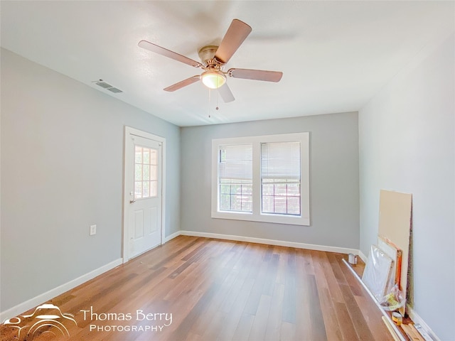 empty room featuring visible vents, ceiling fan, baseboards, and wood finished floors