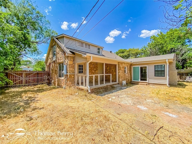 back of house with stone siding and fence