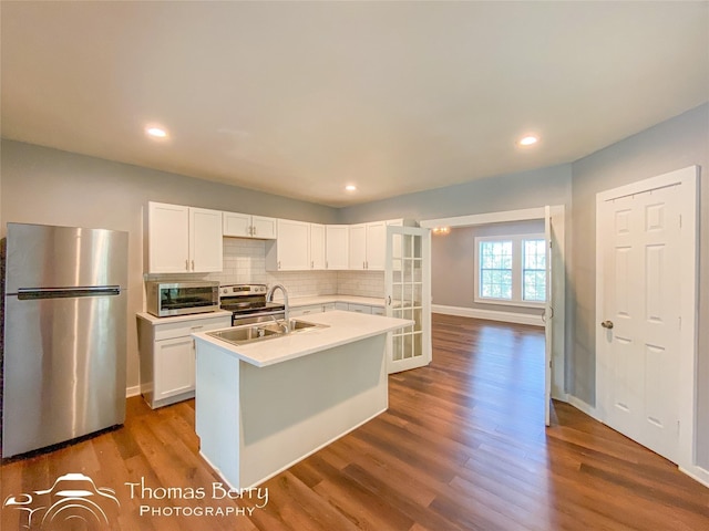 kitchen featuring stainless steel appliances, white cabinets, a sink, and dark wood-style floors