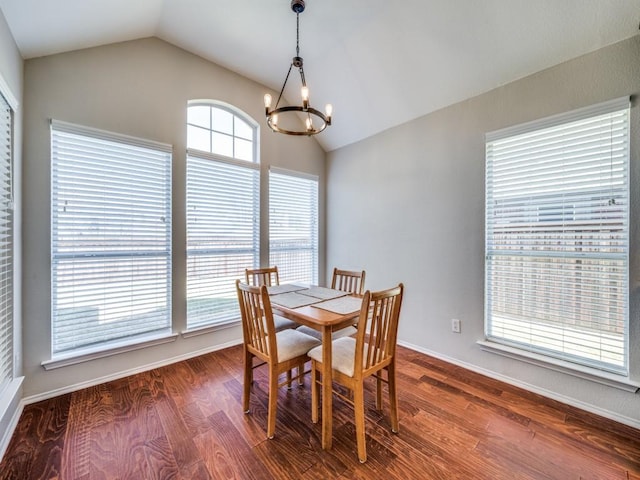 dining room with dark wood finished floors, a notable chandelier, vaulted ceiling, and baseboards